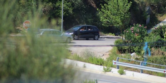 a black car driving down a road next to a forest
